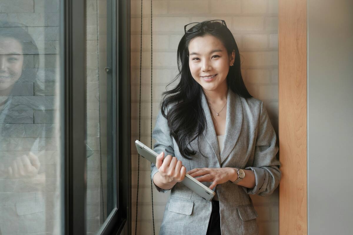 Insurance agent smiling by a window, holding a laptop