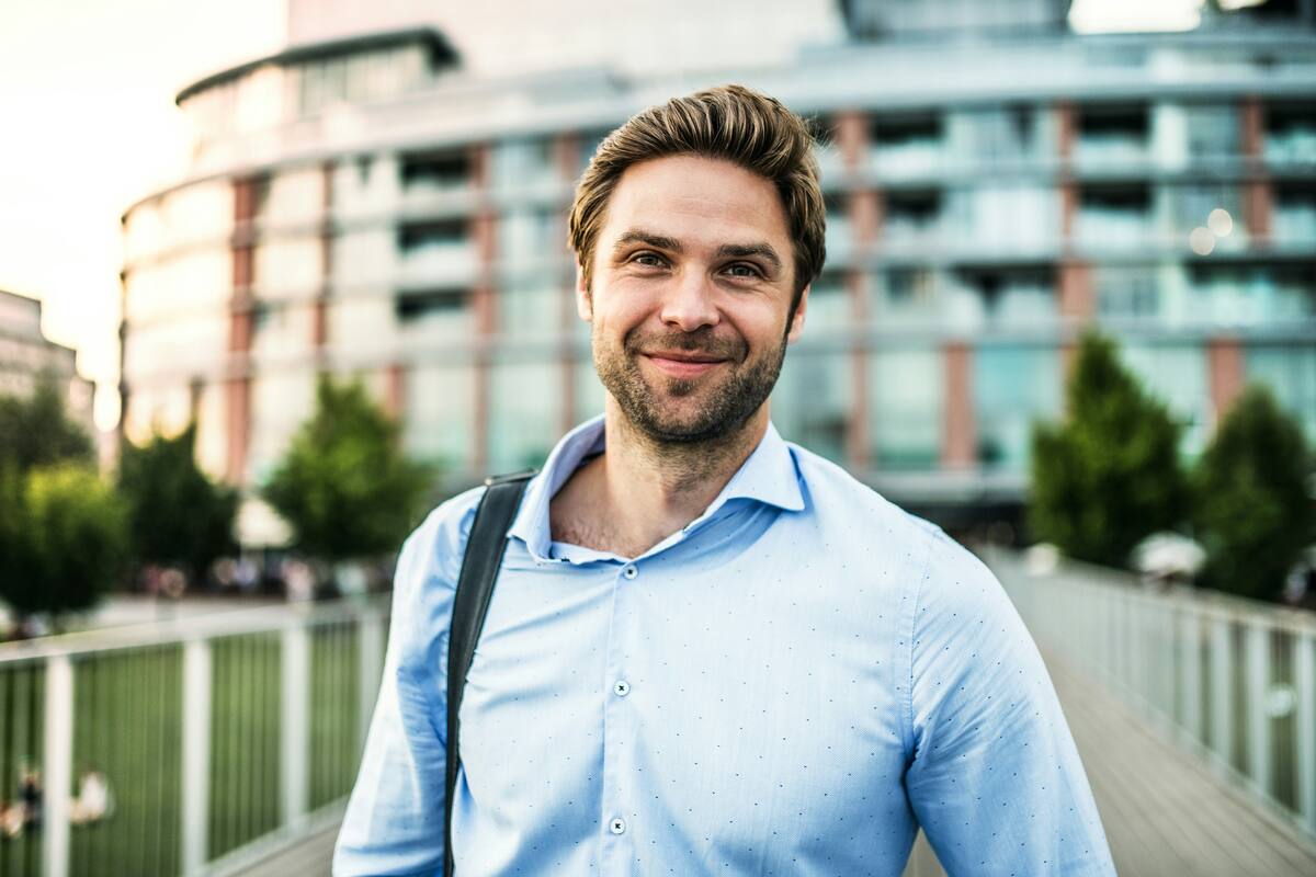 Lender smiling on a city footbridge