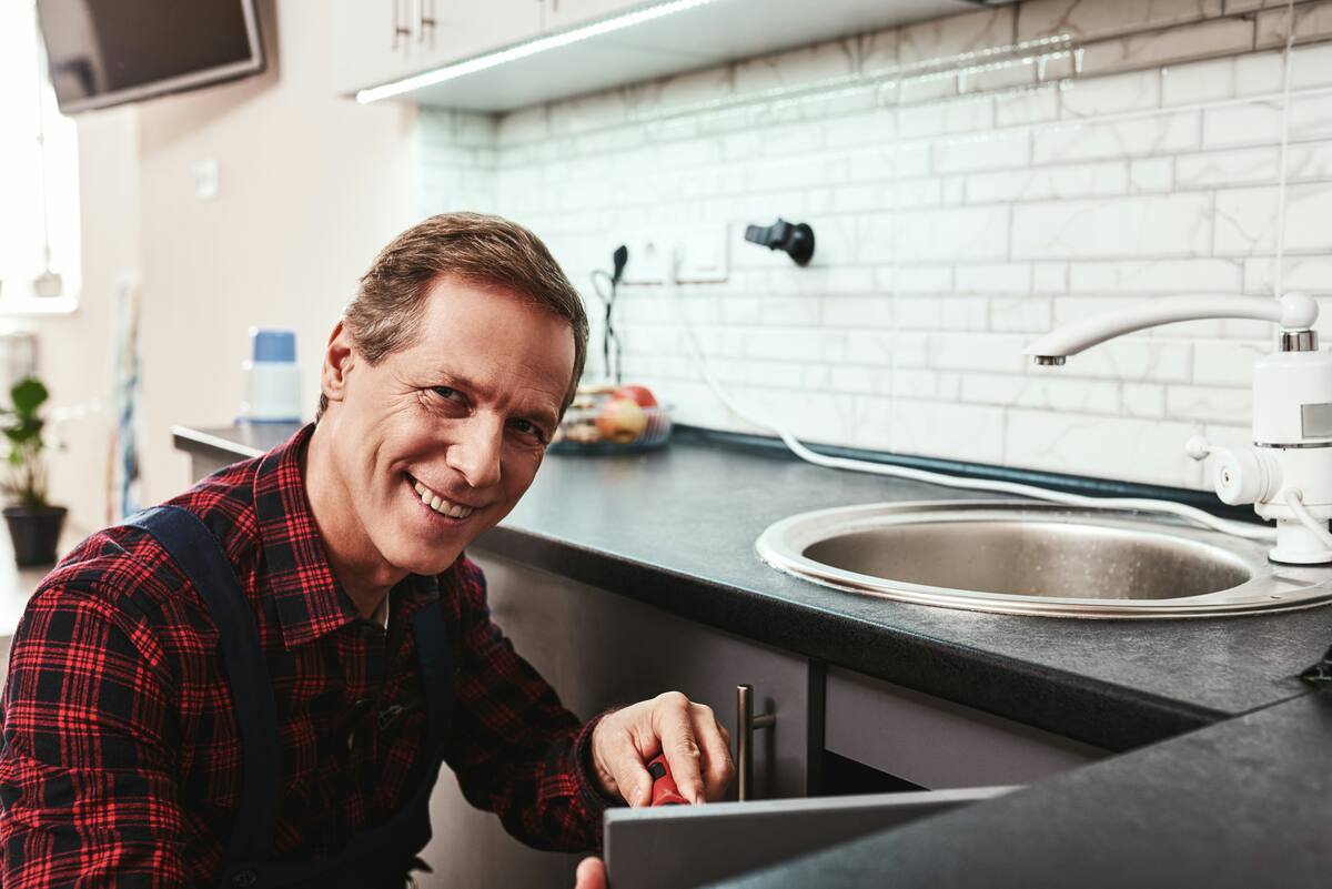 Property manager smiling while fixing a kitchen cabinet